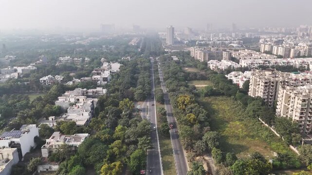 Wide aerial footage of an urban industrial area, highlighting organized infrastructure, low-rise commercial buildings, open plots, and greenery softened by atmospheric haze.