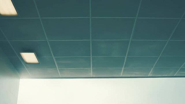Modern office interior featuring a false ceiling with a bright fluorescent light and a window opening to a clear blue sky with fluffy white clouds, symbolizing progress and expansion