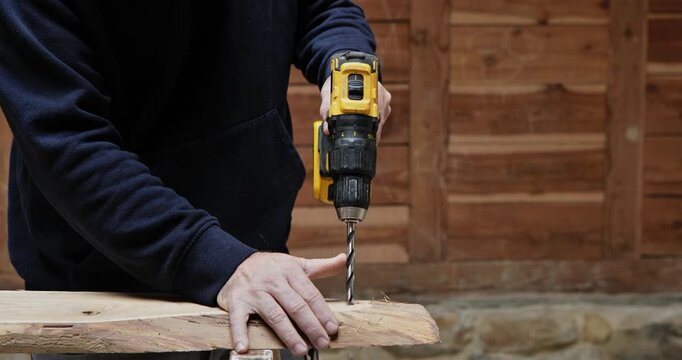 Drilling into the Future: A focused individual drills with precision into a wooden plank, the tool is a symbol of craftsmanship and the potential for creation.