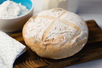Fototapeta premium Freshly baked delicious white bread on a light table on a gray towel. Delicious homemade cuisine