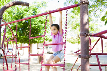 Obraz premium Child playing on monkey bars, exercising and developing strength at a sunny playground during summer