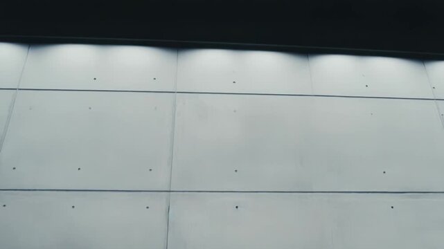 Concrete wall creating a textured background with industrial characteristics, featuring horizontal and vertical lines defining modular panels and visible formwork indentations