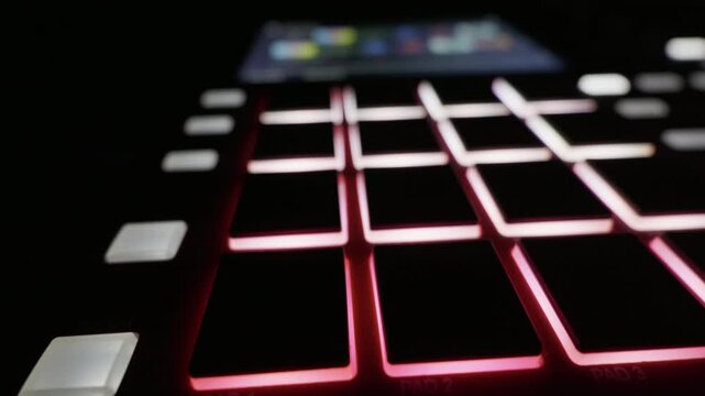 Close up of colorful LED pads on a music sampler lighting up with smooth slider motion. Concept of electronic music production, digital audio technology and beat making.