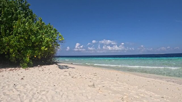 Person walking along white sand beach in Ukulhas Maldives with palm trees and turquoise water