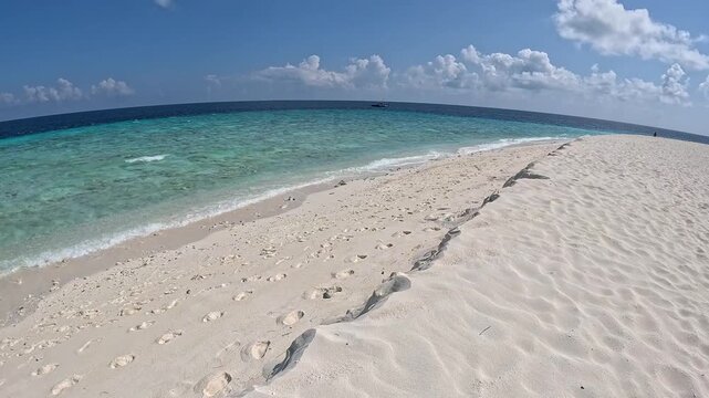 Person walking along white sand beach in Ukulhas Maldives with palm trees and turquoise water