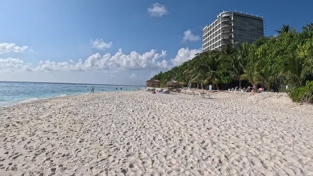 Person walking along white sand beach in Ukulhas Maldives with palm trees and turquoise water