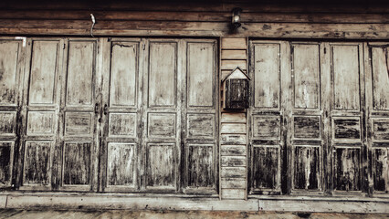 Weathered wooden wall with old doors and lantern, rustic vintage texture, traditional architecture background.