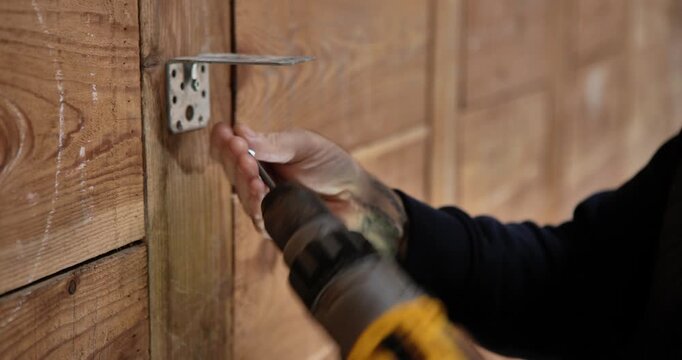 Assembly in Action: Capturing the meticulous process of installing a metal bracket with a power drill onto a wooden surface.