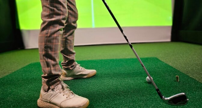 Golf player playing golf indoors on golf simulator closeup