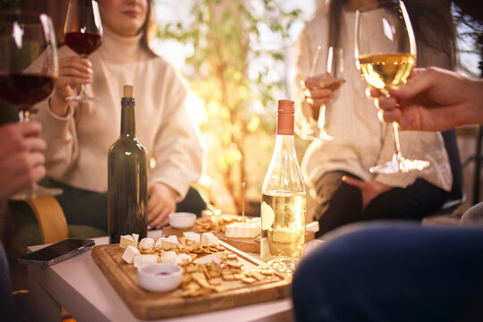 Wine tasting table with snacks and people socializing indoors. Concept of home wine tasting, beverage marketing, lifestyle content, hospitality advertising, and relaxed social interaction.