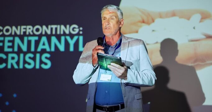 Tablet, stage and man with mic, speech and serious for fentanyl crisis, healthcare and event. Explaining, presentation and public speaking in seminar, communication and mature person in workshop