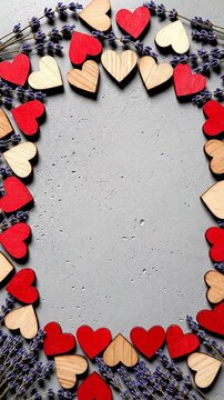 Wooden hearts and dried lavender forming a vertical flat lay frame on gray texture for valentine and romantic copy space.
