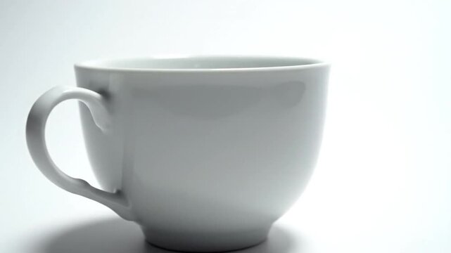 A white ceramic mug with handle on white backdrop. Minimalist design featuring shadow