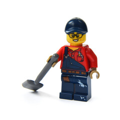 Naklejka premium Lego minifigure of a worker with a shovel isolated on white background. Editorial illustrative image of popular plastic toy.