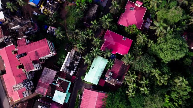 Portuguese style houses with trees and road at colva, south goa, india. day time, top down shot, orbit shot, drone shot, 4k.