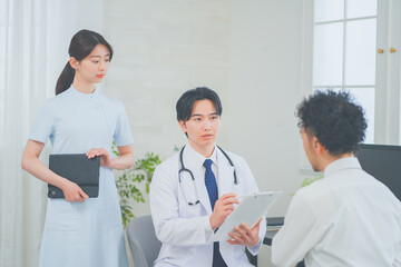 Fototapeta premium 明るく清潔感のあるクリニックで診察をする若い男性医師と女性看護師