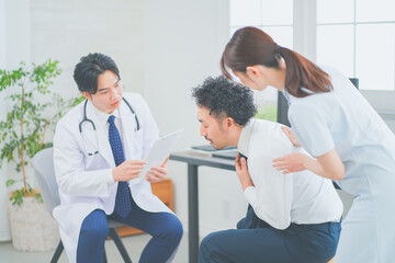 Obraz premium 明るく清潔感のあるクリニックで診察をする若い男性医師と女性看護師