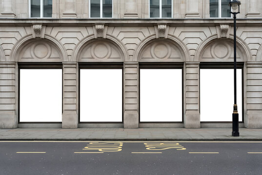 Four blank white store window displays on classic stone building facade near city street for retail advertising