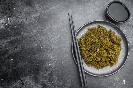 Edible sea grapes also called green caviar and sea caviar with bubble texture in gray bowl on white background Asian cuisine