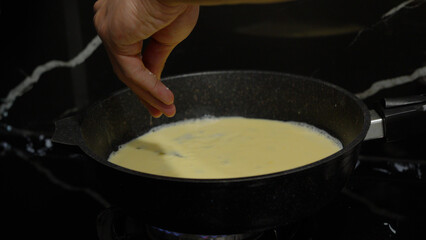 Close up of cooking process with milk in a pan