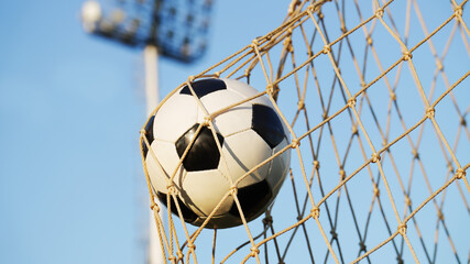 Successful goal scoring in soccer: a ball captured in the net against outdoor stadium background