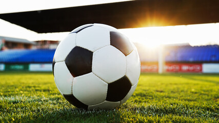 Low angle shot of a football on grass with sun flare, concept of sports motivation and victory