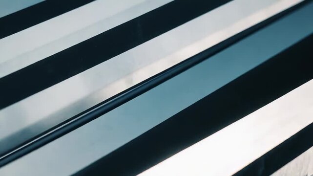Weathered metallic surface with parallel reflective stripes, creating textured geometric pattern, depth and contrast in blue gray steel tones for modern industrial backgrounds