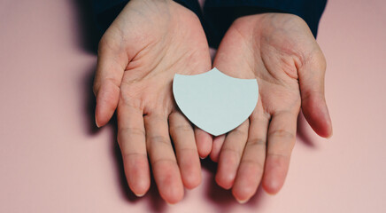 Fototapeta premium Insurance concept. Hands hold blank shield symbolizing protection and security, conveying sense of safety and care