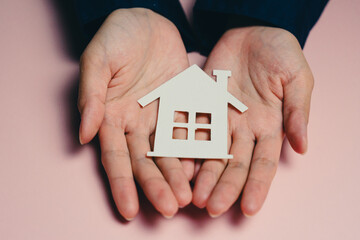 Buying a new house concept. Hands hold small house model, symbolizing home ownership and real...