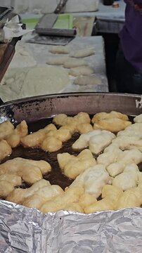Golden Delight: A close-up view of dough being skillfully fried in hot oil, revealing a culinary masterpiece of delicious, golden-brown fried dough sticks in a kitchen.
