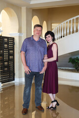 A full-length portrait of married couple in casual wear, indoors.