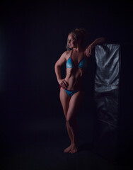 Fototapeta premium Muskulöse, trainierte Bodybuilderin im Best-Age-Alter posiert selbstbewusst im Studio. Symbol für Fitness, Kraft, Disziplin und aktives Älterwerden. Dunkler Hintergrund, Fokus auf Körperform und Stärk