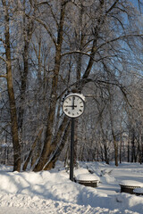 Big clock in winter snowy park