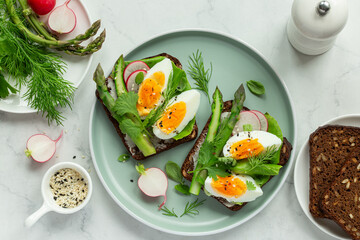 tasty and healthy sandwich with dark rye bread, asparagus and soft boiled egg