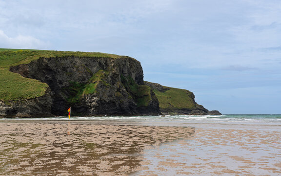 Cornish beach and cliffs in summer with lifeguard flag