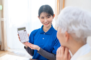 シニアに電卓を見せる女性