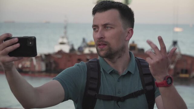 Human journalist make report on sunken tanker Delfi in Odessa. Male blogger shoots video on phone, publish post about ship wreck in Black Sea. Man video blogger tell subscriptions about boat accident.