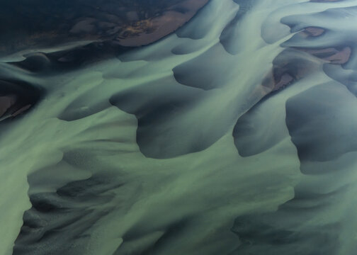 Aerial view of glacial rivers intertwine like veins across the stark landscape, creating a mesmerizing dance of turquoise and ochre hues, Selfoss, Sveitarfelagid Arborg, Iceland.