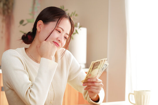 お金を見つめて遣い方を考えている若い女性