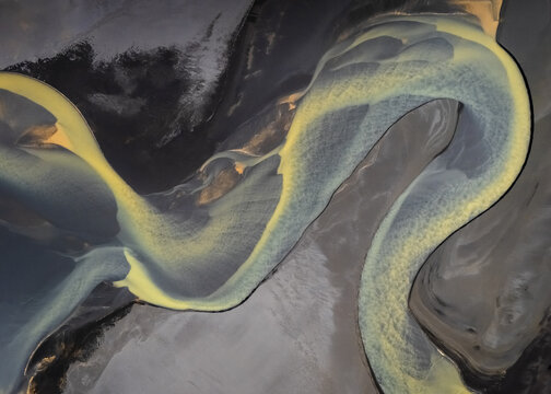 Aerial view of winding glacial river carves through the landscape, a tapestry of ochre and slate creating nature's abstract masterpiece, Selfoss, Sveitarfelagid Arborg, Iceland.