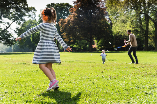 Girl with family wearing headphones in a park
