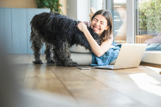 Happy young woman with dog lying at the window at home