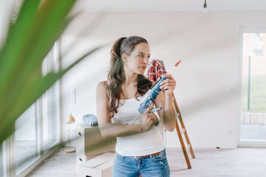 Mature woman moving house holding glue gun