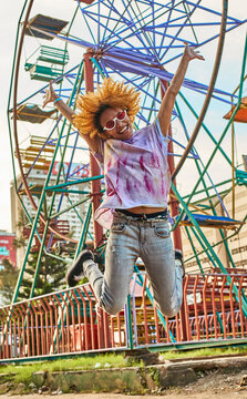 Happy woman jumping in front of a Ferris wheel