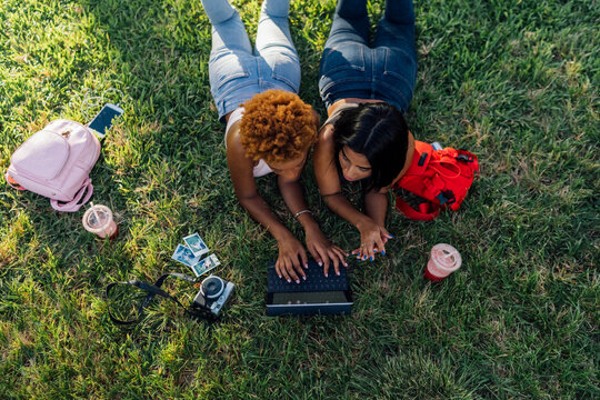 Two female friends relaxing in a park using a tablet