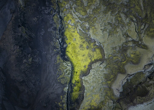 Aerial view of the stark, moss-covered terrain, contrasting sharply with the dark volcanic earth, creates an otherworldly tapestry of textures and tones, Flugir, Rangarthing ytra, Iceland.