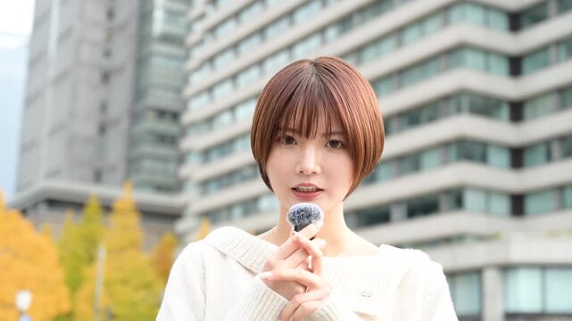 カメラ目線でピンマイクを使って話す日本人女性