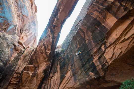 USA, Utah, Moab, Canyonering, Woman rapelling down a giant arch