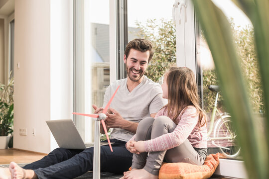 Young man and little girl playing with model of a wind turbine