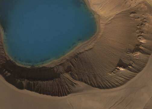 Aerial view of a serene turquoise lake nestled within a Martian landscape of ochre and umber, contrasting sharply with the rugged terrain, Flugir, Rangarthing ytra, Iceland.